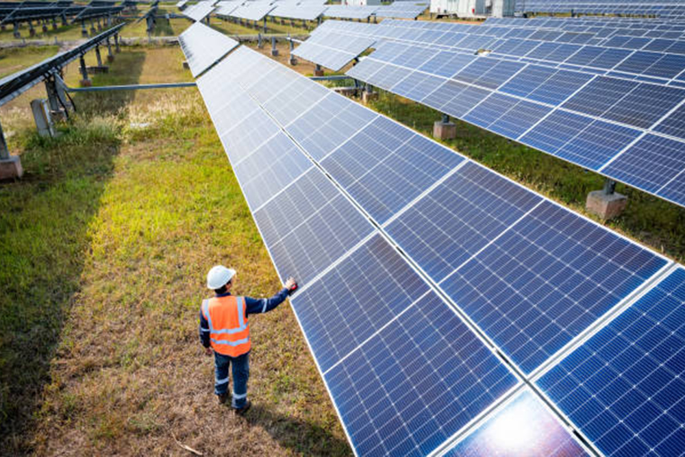 太阳能农场(太阳能电池板)有工程师检查系统的运行情况，替代能源节约世界能源，光伏组件生产清洁能源的想法。