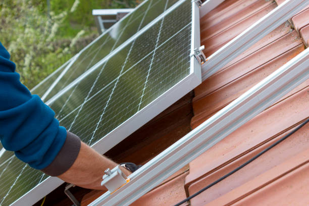工人在屋顶上安装太阳能电池板。替代能源概念。